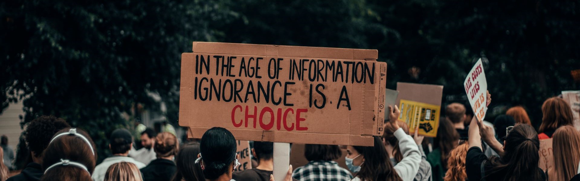 Crowd with a sign ignorance in information age is a choice