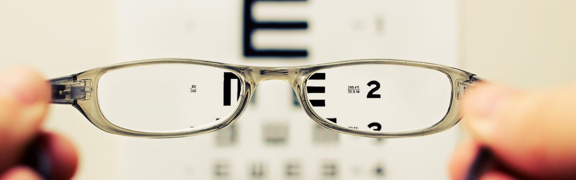 Hand holding glasses over an eye examine board